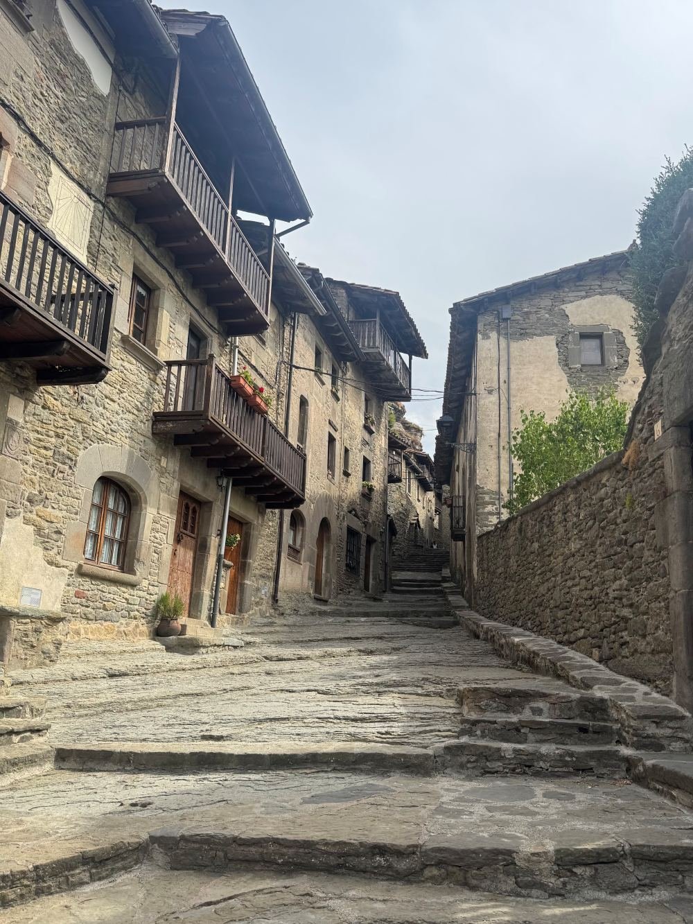Calle empedrada con balcones de madera y casas de piedra en el casco antiguo de Rupit